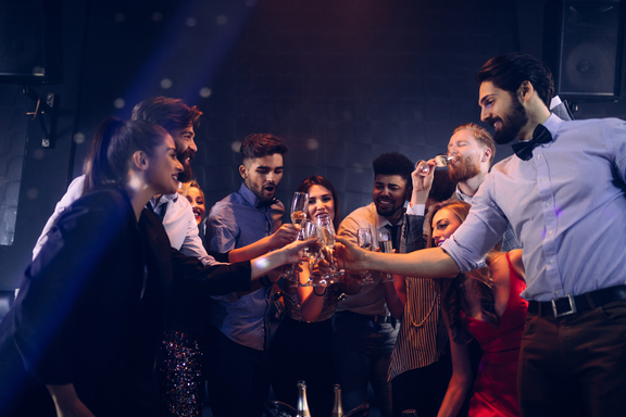 Pals celebrating with champagne and partying into the night at a bar with a late extension